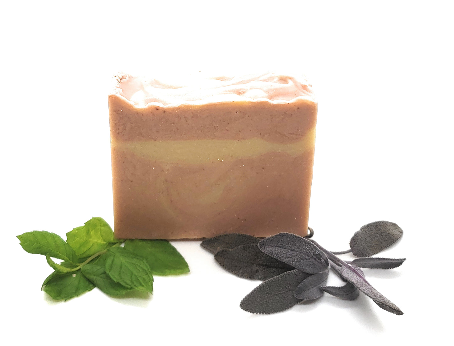 Pink ombre goat's milk soap on a white background with peppermint and sage fresh herbs.  Patchouli, peppermint and clary sage goat's milk soap